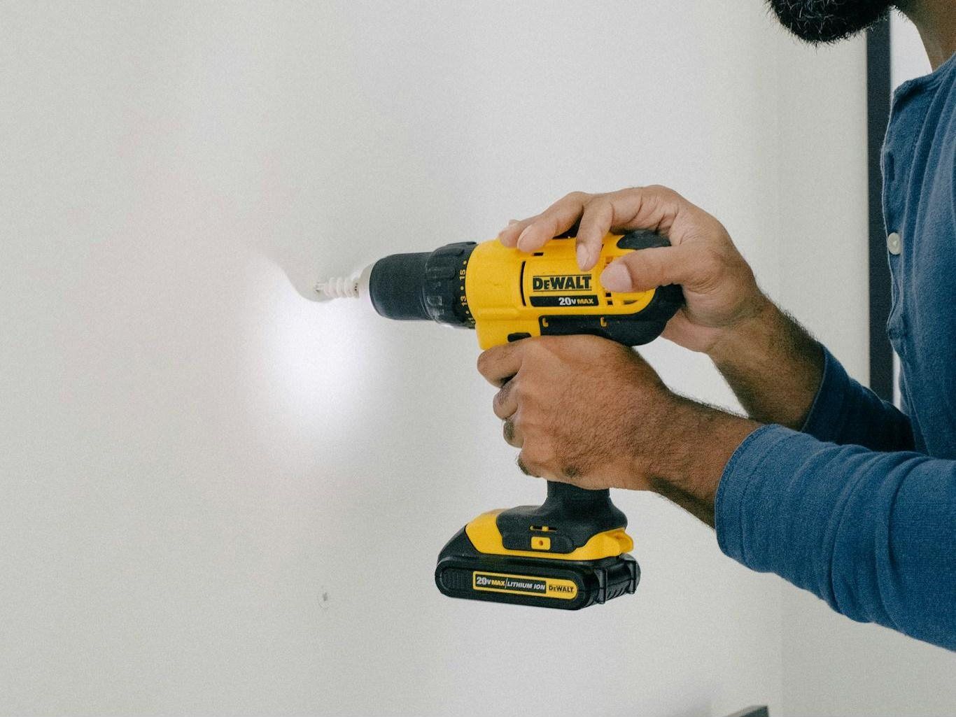 Tradesperson repairing a timber deck with a drill